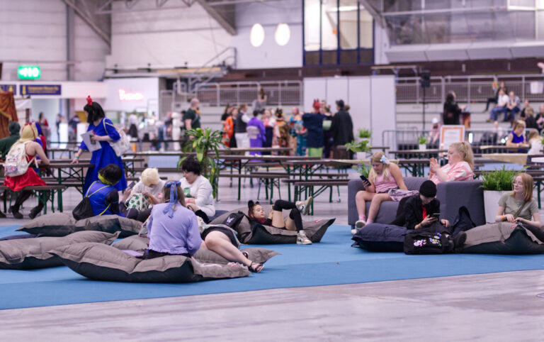 Ihmisiä istumassa messukeskuksella, osa istuu sohvalla ja osa pehmeillä säkkituoleilla.